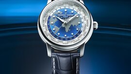 A silver-blue wristwatch by Frederique Constant featuring a globe on the dial and a black leather strap.