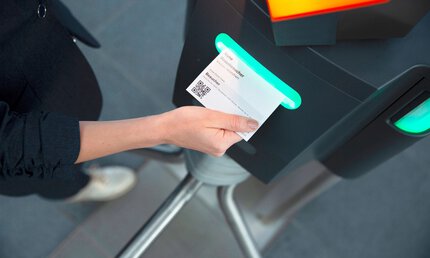 Person, die ein QR-Code-Ticket an einem automatischen Drehkreuz scannt.