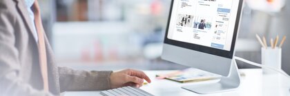 Ein Mann sitzt vor einem Computerbildschirm an einem Schreibtisch und scrollt durch den Ausstellershop der transport logistic.