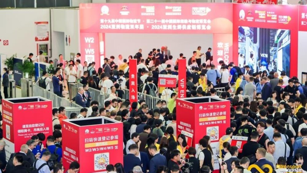Numerous visitors to transport logistic CHINA are waiting to enter the trade fair. Between them are red square advertising pillars for the event.