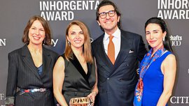 A man and three women in festive attire stand smiling in front of a photo wall of the INHORGENTA AWARD, holding a trophy.