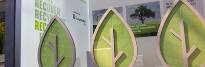 Exhibition stand with large leaf motifs promoting reuse and recycling as environmentally friendly practices.