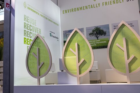 Ausstellungsstand mit großen Blattmotiven, der Wiederverwendung und Recycling als umweltfreundliche Praktiken fördert.