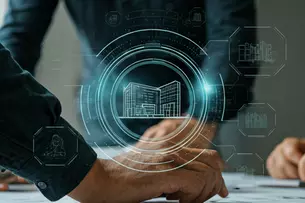 Several people discuss architectural plans while a digital building hologram is projected above the table.