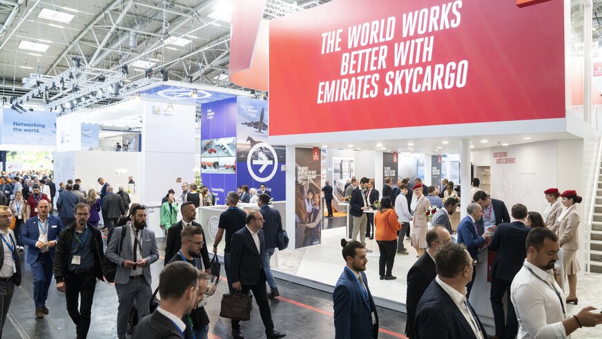 Visitors to the transport logistic trade fair cavort in an exhibition hall between various stands on the subject of air freight.