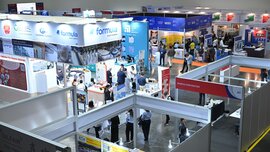 View across numerous exhibition stands at ceramitec, between which visitors walk and gather information from exhibitors.