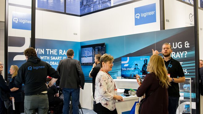People interact at a busy trade fair booth with “Made in Germany” signs and Logineer branding.