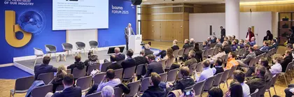 Vortrag beim bauma FORUM 2025 mit einem Redner am Podium und zahlreichen sitzenden Zuhörern in einem modernen Konferenzraum.