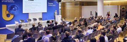 Vortrag beim bauma FORUM 2025 mit einem Redner am Podium und zahlreichen sitzenden Zuhörern in einem modernen Konferenzraum.