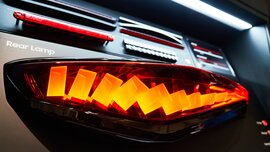 Illuminated modern car tail lights with different light patterns and designs on display.
