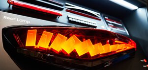 Illuminated modern car tail lights with different light patterns and designs on display.