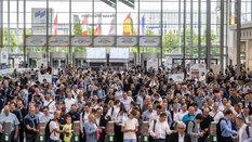 A large crowd gathers in front of the ticket barriers in the West Entrance Hall.