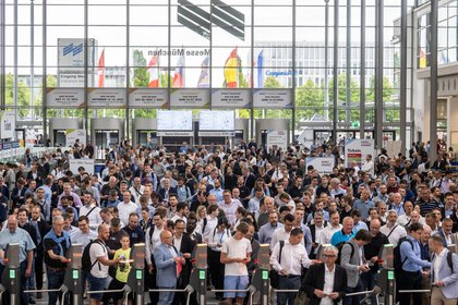 A large crowd gathers in front of the ticket barriers in the West Entrance Hall.