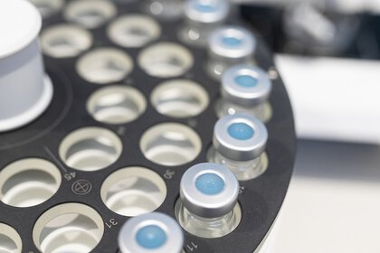 Close-up of an analyzer: Several vials with aluminum septum caps are arranged in a circle in round holders.