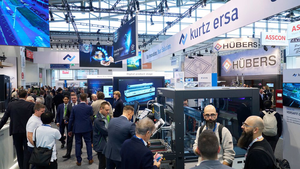 Numerous trade fair visitors stand between the machines and displays at various stands at productronica.