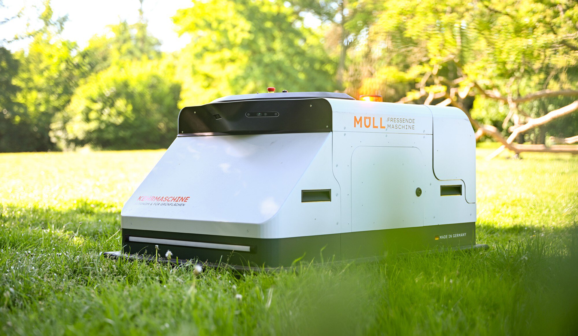 A robot from Angsa Robotics drives across a meadow and picks up trash.