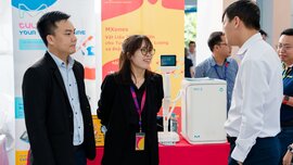 Drei Personen im Gespräch an einem Messestand mit Laborgeräten und Infomaterialien von Merck und Sigma-Aldrich auf einer Wissenschaftsmesse.