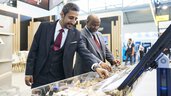 Two men in suits examine the materials on display at an exhibition stand.