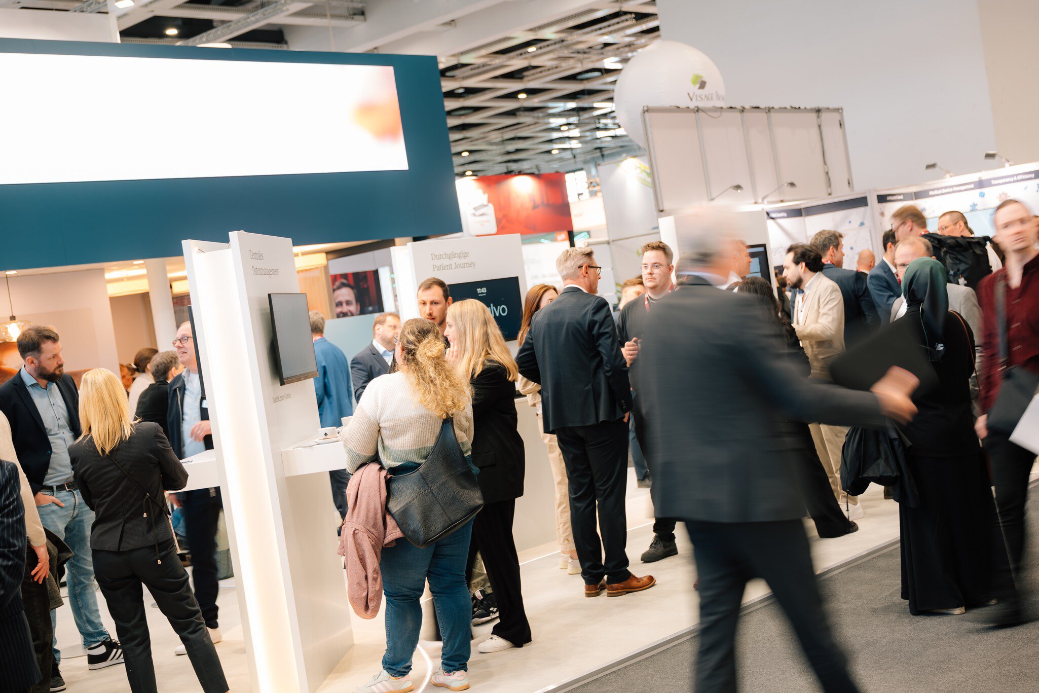Professional attendees networking at a DMEA exhibition booth