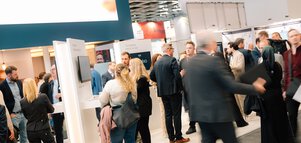 Professional attendees networking at a DMEA exhibition booth