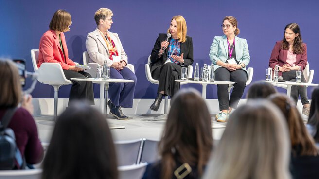 Five women on stage at a forum