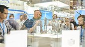 Besucher betrachten Exponate in einer Vitrine auf der Laser World of Photonics 2025 in München.