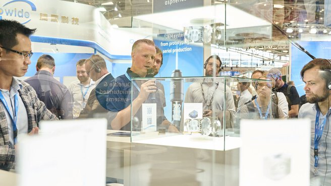 Besucher betrachten Exponate in einer Vitrine auf der Laser World of Photonics 2025 in München.