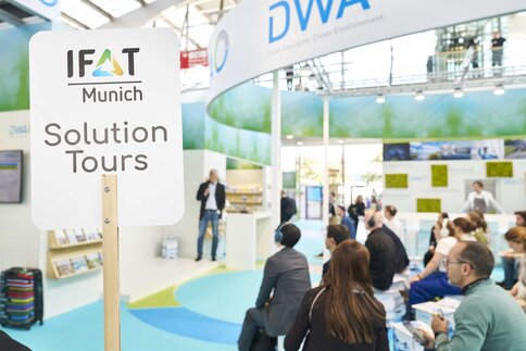 Personen die als Teil der IFAT Munich Solution Tours an einem Vortrag auf einem Messestand teilnehmen.