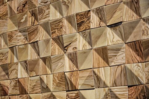 Close-up of a wall covered with square, wood-textured tiles that form a geometric, three-dimensional pattern.