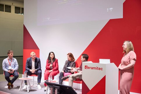 Panel discussion on the ceramitec stage with several participants and a moderator.
