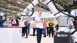 Vortrag auf einem Messestand mit Publikum im Hintergrund