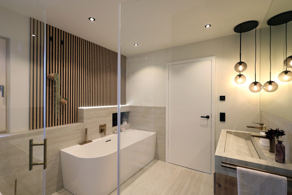 Modernes Badezimmer mit Badewanne, Holzlamellen an der Wand und hängenden Kugelpendelleuchten über dem Doppelwaschbecken.