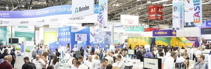 Many people in an exhibition hall gather information at various stands