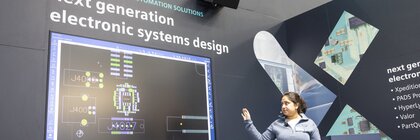 An exhibitor is giving a lecture next to a screen with the text 