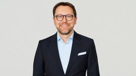 In the picture, you can see Stefan Rummel, CEO of Messe München Group, wearing a suit and smiling.