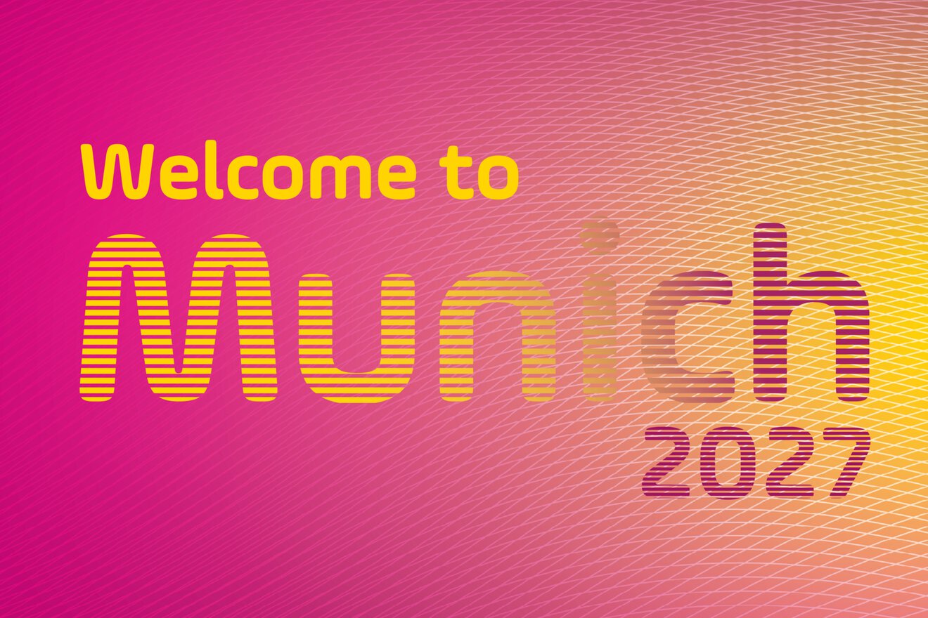 The pink and yellow poster reads: “Welcome to Munich 2027, DMEA Munich April 13-15, 2027, Connecting Digital Health.”