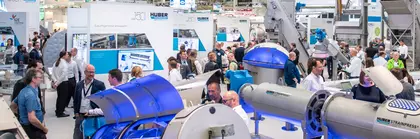 Trade fair visitors look at industrial machinery on display at a large stand in Hall A2.