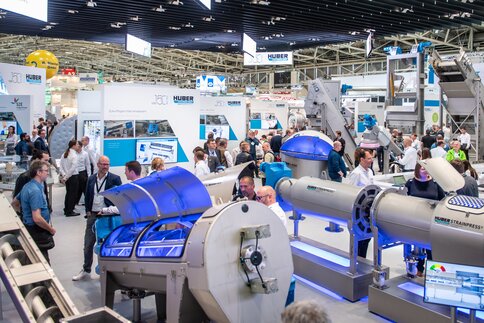 Trade fair visitors look at industrial machinery on display at a large stand in Hall A2.
