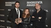 Three people holding the trophy for the “Fashion Jewelry of the Year” category smiling in front of a logo wall at the AWARD Gala.