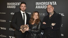 Three people holding the trophy for the “Fashion Jewelry of the Year” category smiling in front of a logo wall at the AWARD Gala.