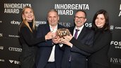 Four people smile and hold the trophy for the “Fine Jewelry of the Year” category in front of a logo wall at the INHORGENTA AWARD Gala.