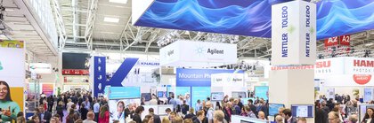 Hall impression in exhibition hall A2 during analytica with many people at exhibition stands of various companies such as Mettler Toledo, Agilent or Hamamatsu