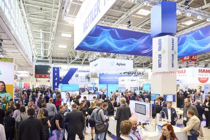 Hall impression in exhibition hall A2 during analytica with many people at exhibition stands of various companies such as Mettler Toledo, Agilent or Hamamatsu