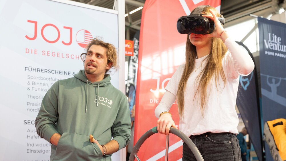 Ein Mädchen probiert VR-Brille aus mit Unterstützung von einem Mann