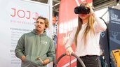 A girl tries on VR goggles with the help of a man