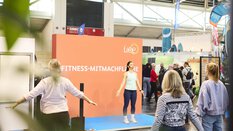 Trainer leads a fitness session in the hands-on area at the “f.re.e” trade fair, while visitors actively participate.