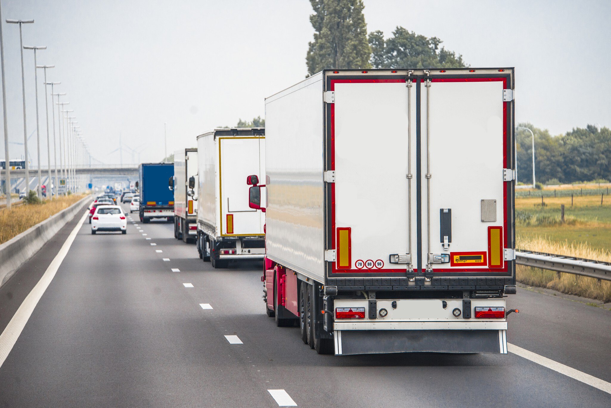 Several trucks driving on a two-lane highway.