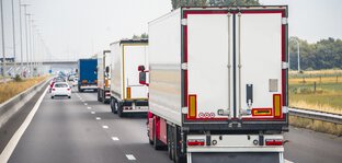 Several trucks driving on a two-lane highway.