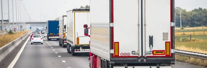 Several trucks driving on a two-lane highway.