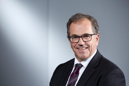 Man in suit with tie and glasses posing with a smile.
